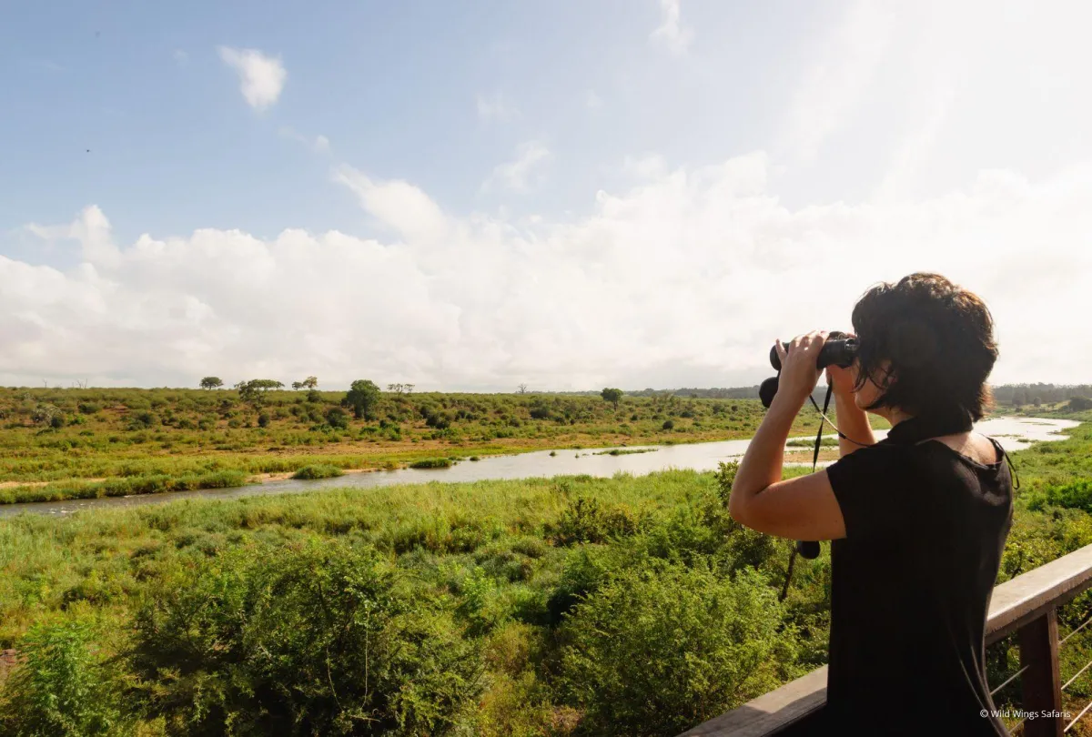 Woman-standing-at-a-lookout-point-looking-through-binoculars-at-the-opposite-riverbank_159e2d090b2edcff8ce42a6e3e5a91c9